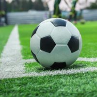 soccer ball with his feet on the football field